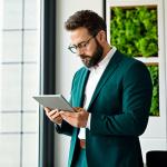 A professional architect, focused and thoughtful, wearing a modest business suit, reviewing digital blueprints on a tablet in a modern, sustainable office space. The office features large windows with natural light, a green wall in the background, and a collection of professional books on sustainable design. The architect's posture is natural and engaged, reflecting deep concentration. Perfect anatomy, correct proportions, natural pose, well-formed hands, proper finger count, natural body proportions. Fully clothed, appropriate attire, professional dress, safe for work, appropriate content, family-friendly, high quality, professional photography.